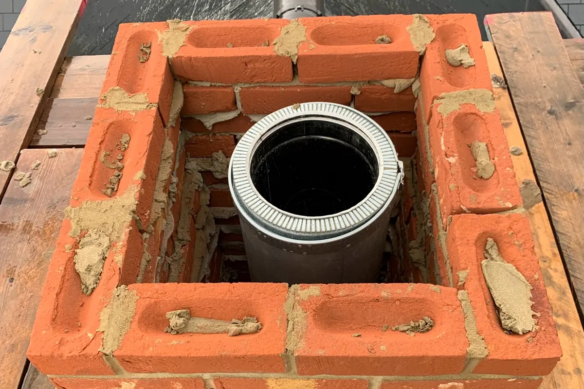 Top-down view of newly installed insulated flue liner positioned within rebuilt chimney stack