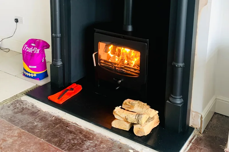 Wood-burning stove installation in Faversham, Kent, including a new hearth and fireplace surround, with the appliance demonstrated fully loaded and operating during the customer handover.