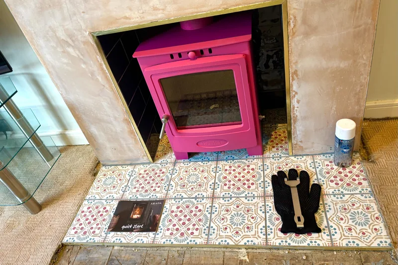 Wood-burning stove installation in Whitstable, Kent, customised to the customer’s specification with a bright pink appliance finish and matching pink tiled hearth.